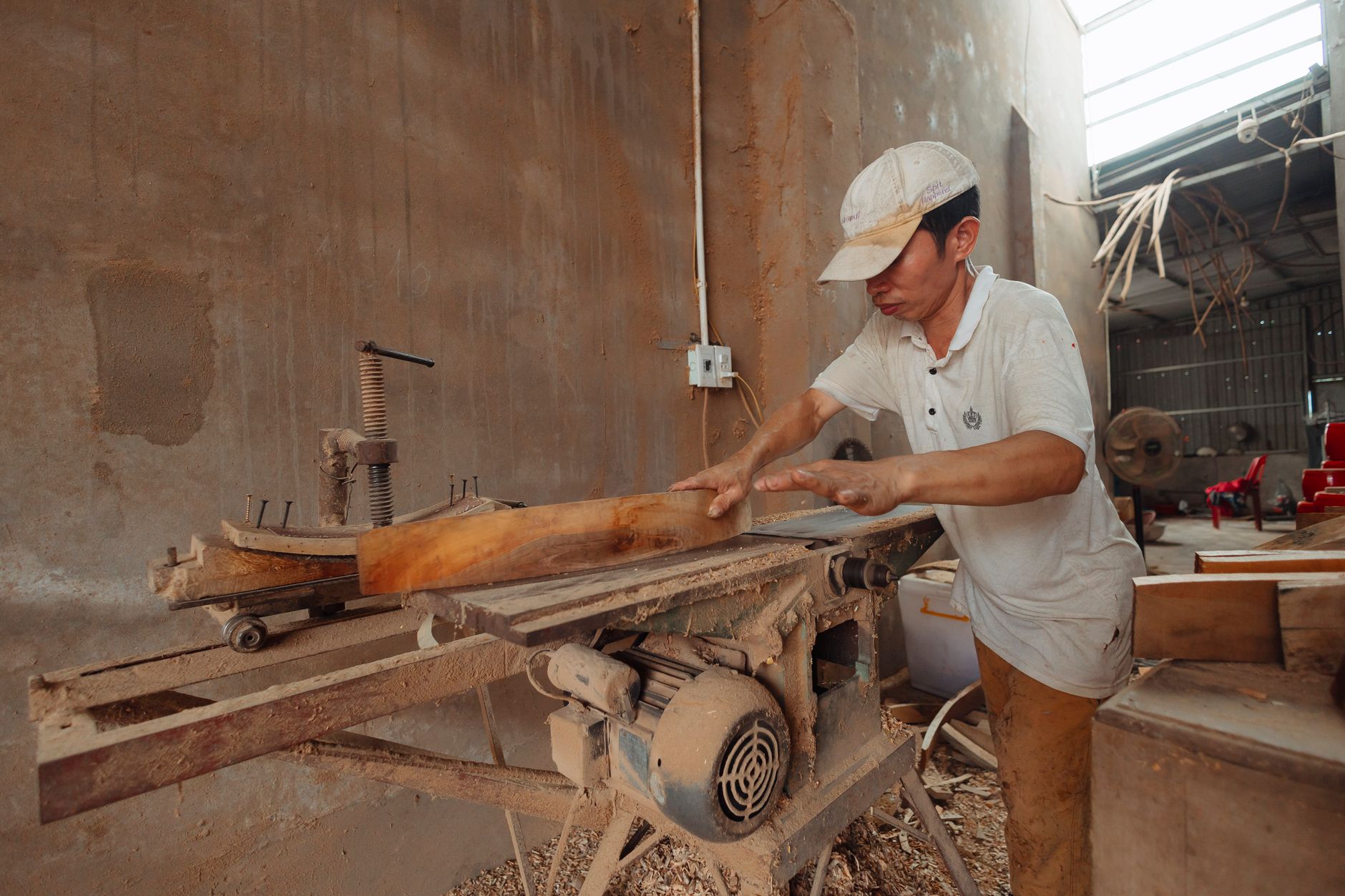 Carpenter running a board through a planer in the workshop