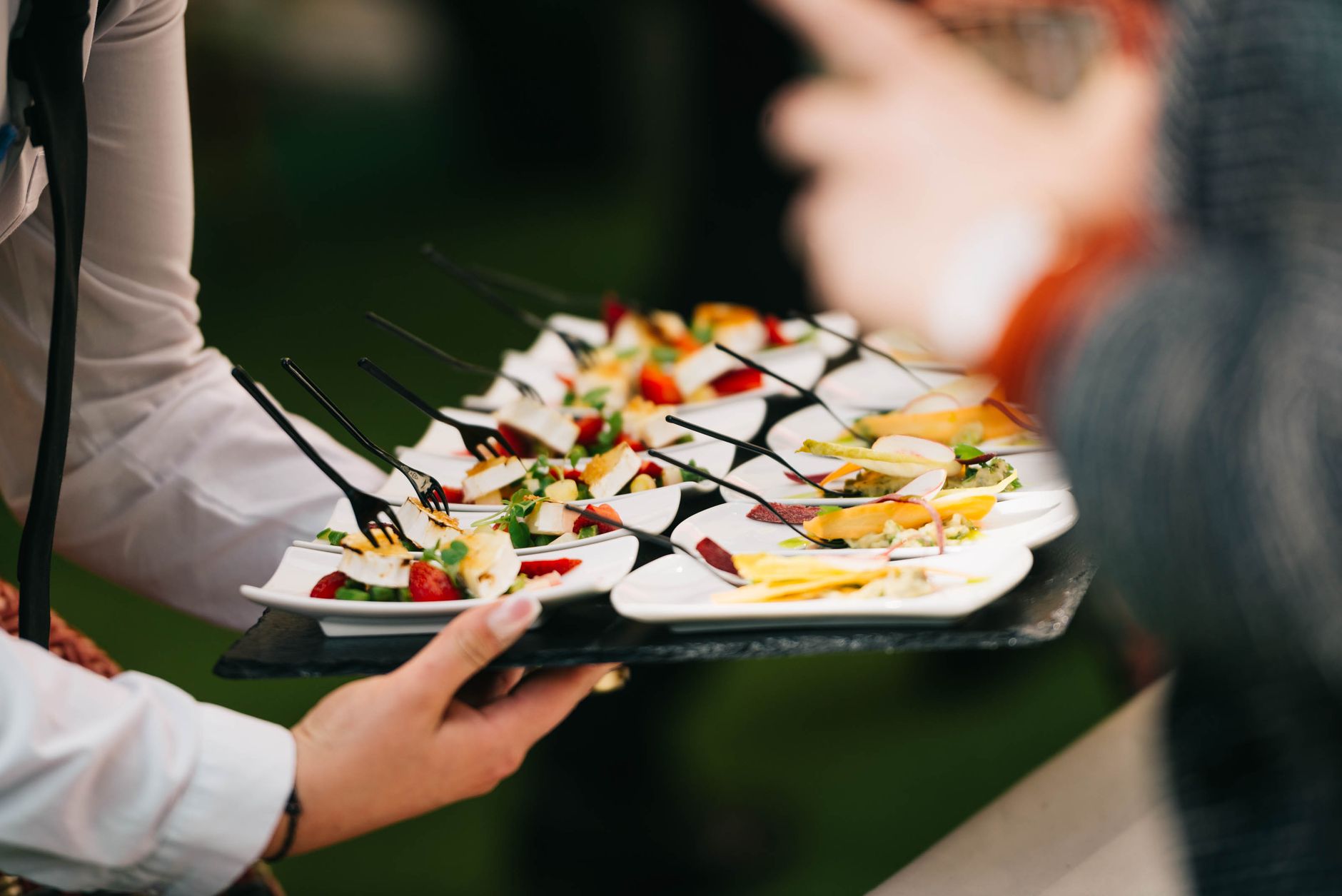 Server carrying a tray of plated canapes