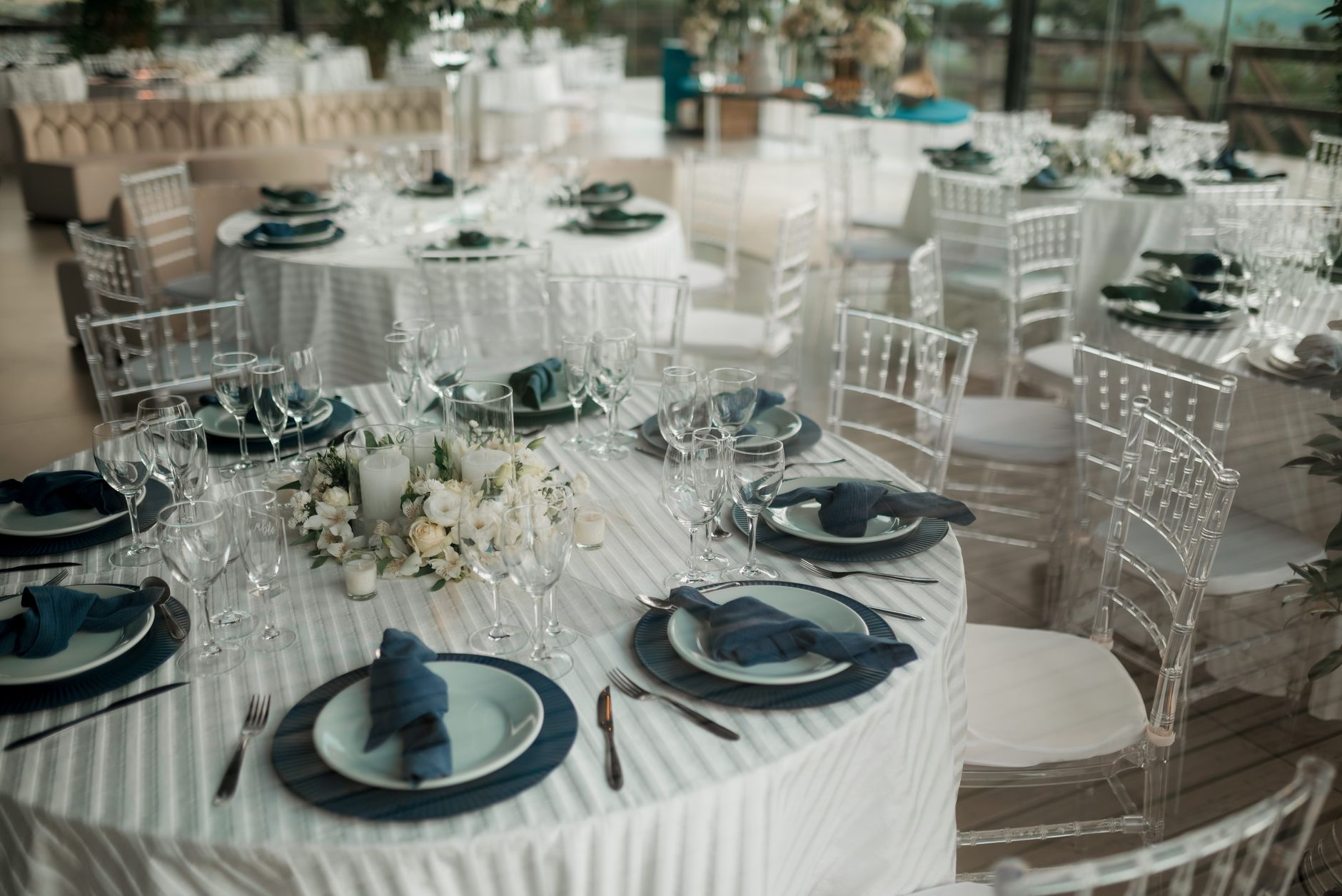 Wedding reception hall with round tables and blue napkins